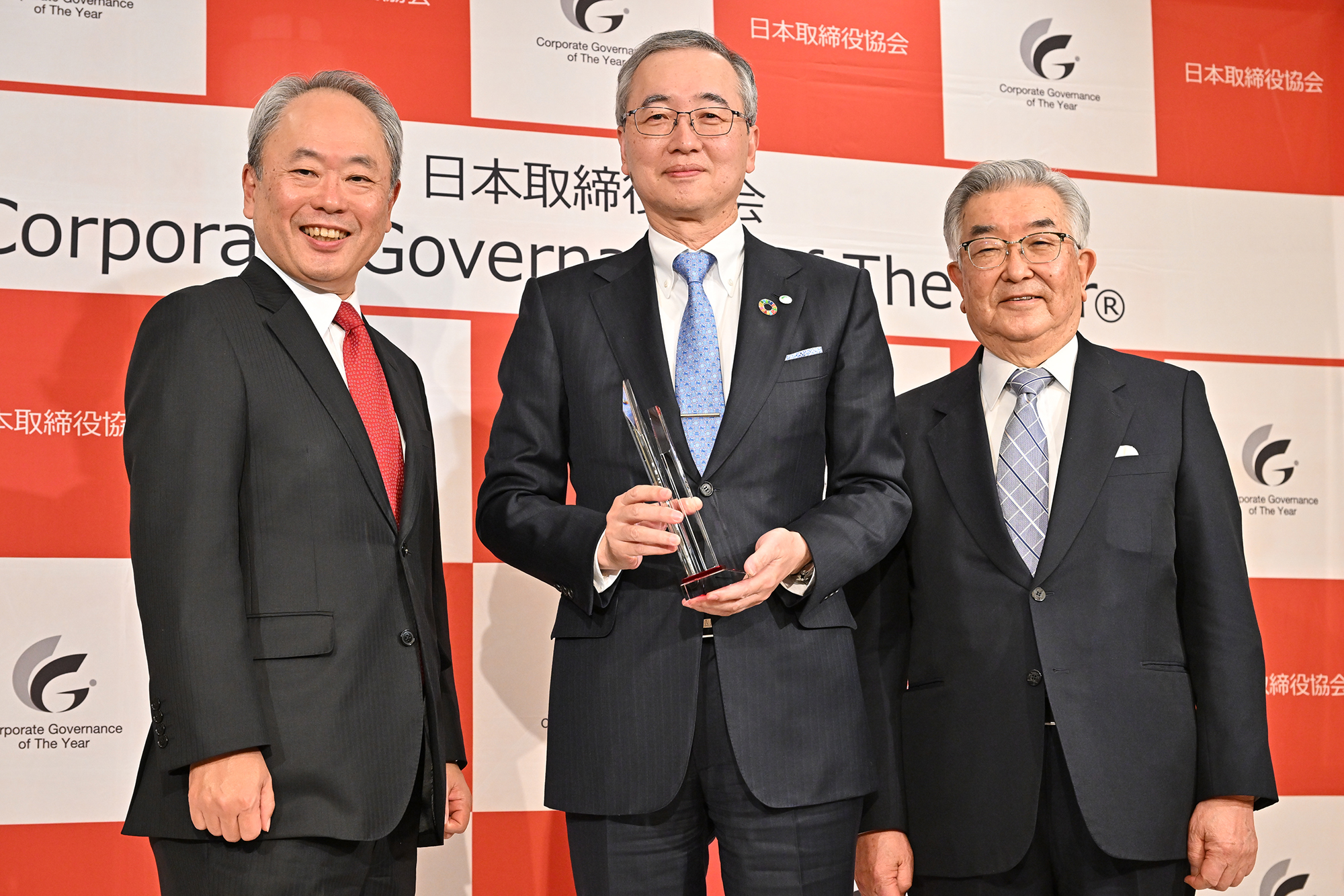 中央に小島啓二様、左にプレゼンターの冨山和彦、右に審査委員長の斉藤惇様